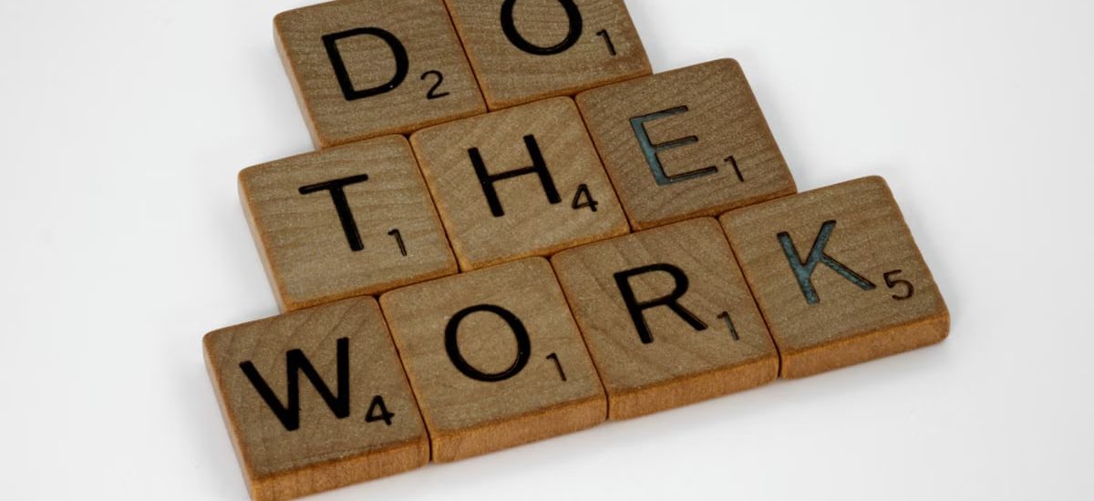Creative arrangement of Scrabble tiles spelling 'Do the Work' on a white background.