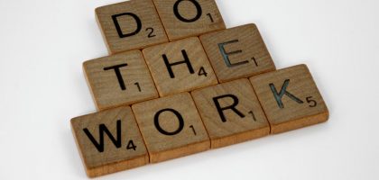Creative arrangement of Scrabble tiles spelling 'Do the Work' on a white background.