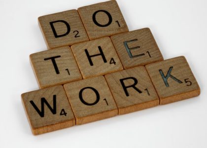 Creative arrangement of Scrabble tiles spelling 'Do the Work' on a white background.